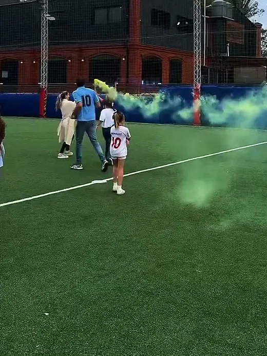Bengala de humo verde al costado de la cancha durante un cumple