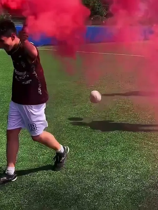 Un chico corriendo con una bengala de humo rojo en la cancha