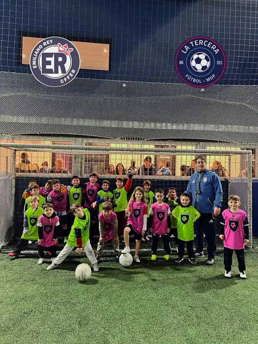 Chicos de la escuelita con el profe en la cancha